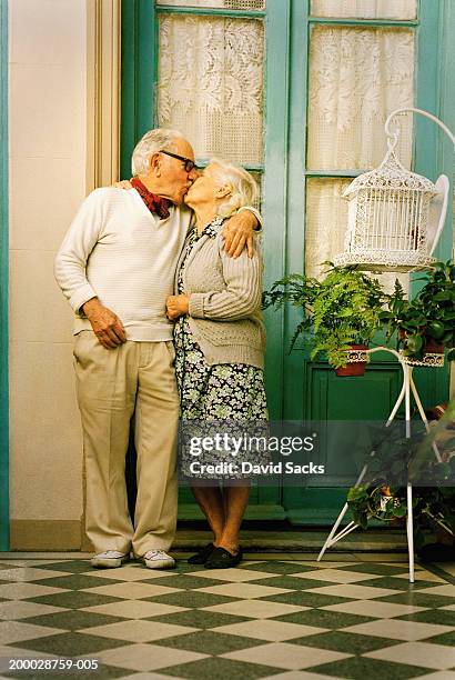 elderly couple kissing outside house - kissing stock pictures, royalty-free photos & images