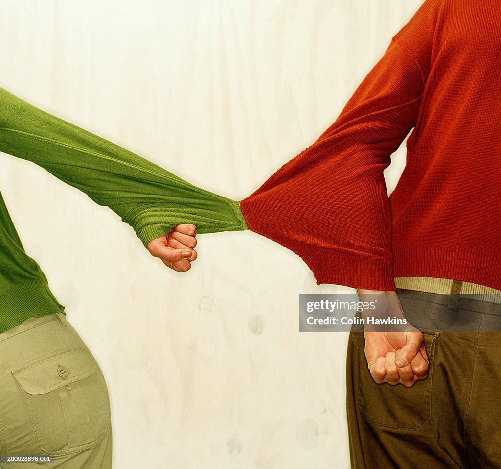 Man and woman with sweater sleeves stitched together, rear view