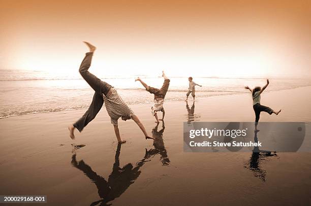 family doing cartwheels and dancing on beach - cartwheel stock pictures, royalty-free photos & images