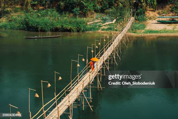 monk walking over the bridge on mekong river - laos stock pictures, royalty-free photos & images