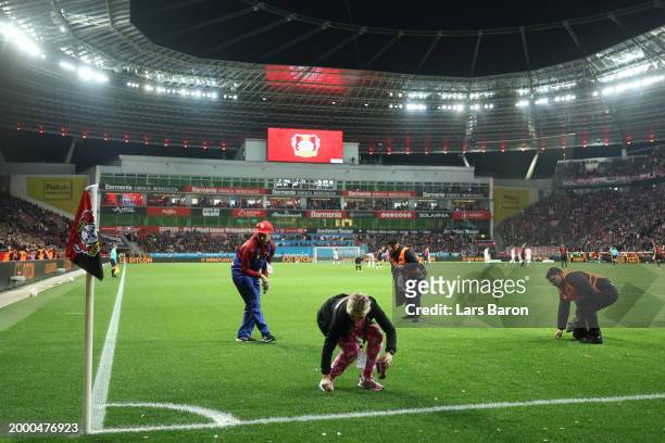 Stewards collect sweets that have been thrown on the pitch during the Bundesliga match between Bayer 04 Leverkusen and FC Bayern München at BayArena...