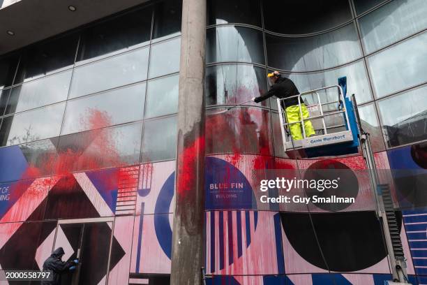 Workers clean red paint from a building used by BAR Systems after an early morning protest by Palestine Action on February 10, 2024 in London,...