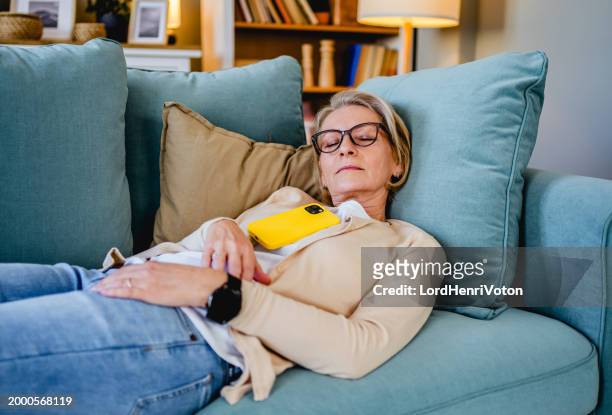 müde frau macht ein nickerchen auf dem sofa - woman taking a nap stock-fotos und bilder