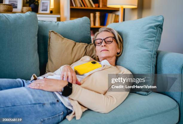 tired woman taking a nap on the sofa - dormitar imagens e fotografias de stock