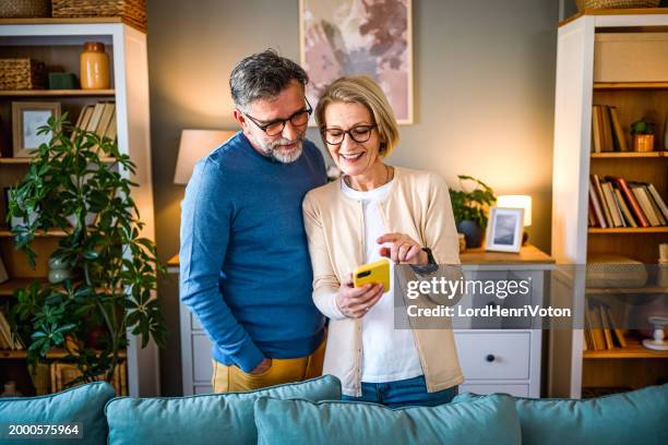mature couple using mobile phone - couple getting along stock pictures, royalty-free photos & images
