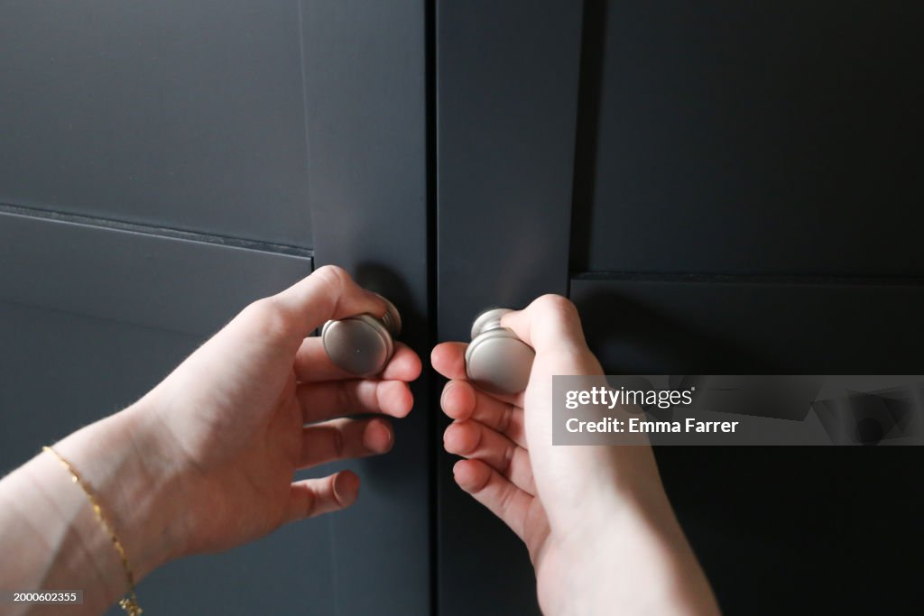 Hands opening a pair of wooden doors
