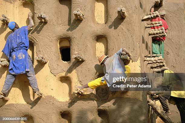 mali, dogon country, men plastering mosque with mud - dogon stock pictures, royalty-free photos & images