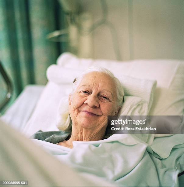 elderly woman smiling, lying in hospital bed, portrait - patient portrait stock pictures, royalty-free photos & images