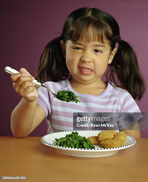 girl (5-7) making a face at fork full of spinach, portrait - lustig bunt bildbanksfoton och bilder