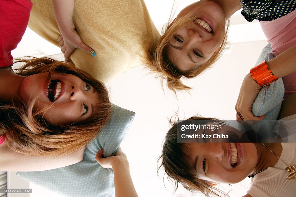 Three teenage girls (16-18) with pillows, smiling, low angle view