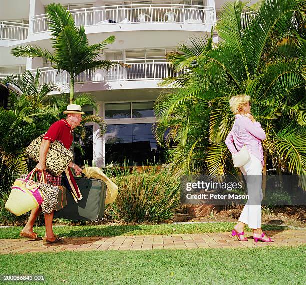 mature couple at resort, man struggling with suitcases - carrying luggage stock pictures, royalty-free photos & images