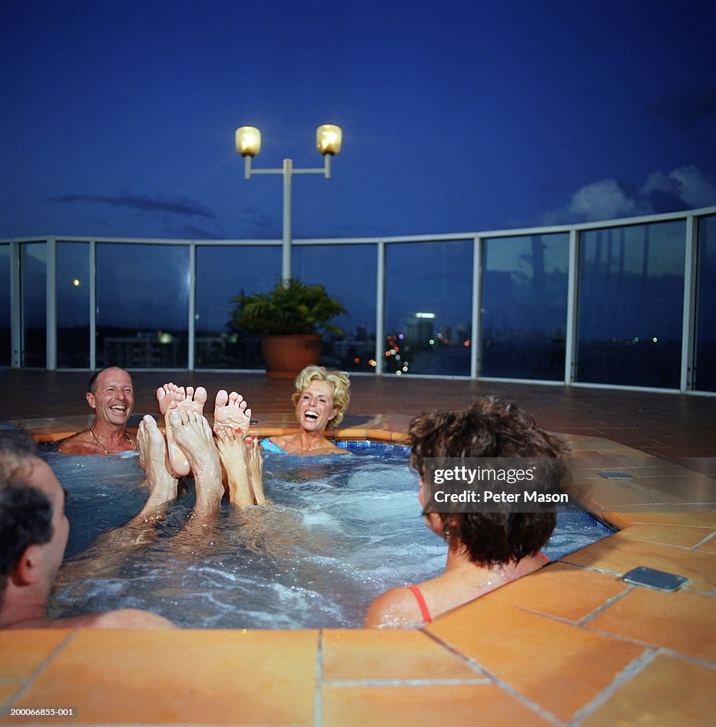 Two mature couples playing footsie in hot tub