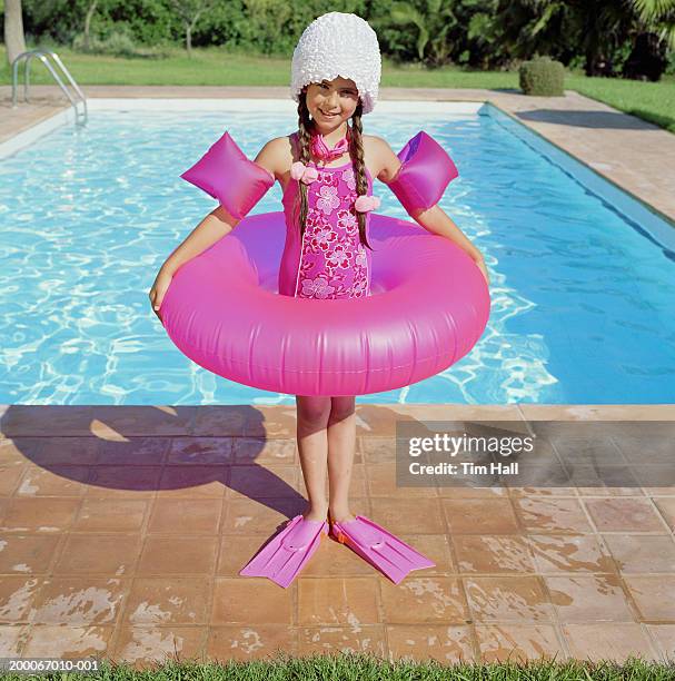 girl (6-8) standing in inflatable ring by swimming pool, portrait - tube girl stock-fotos und bilder