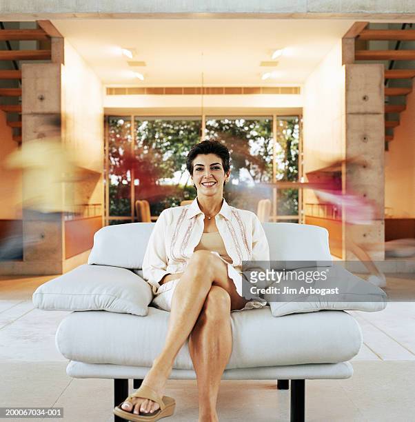 woman sitting in armchair, children running behind her (long exposure) - incidental people stock pictures, royalty-free photos & images