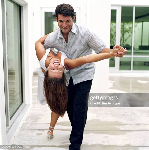 man dipping woman while dancing on patio - dippen stock-fotos und bilder