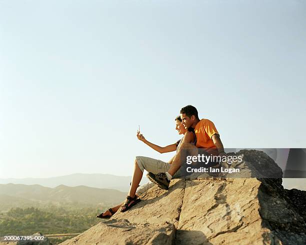 couple sitting on top of mountain, using mobile camera phone - two women on phone isolated stock pictures, royalty-free photos & images