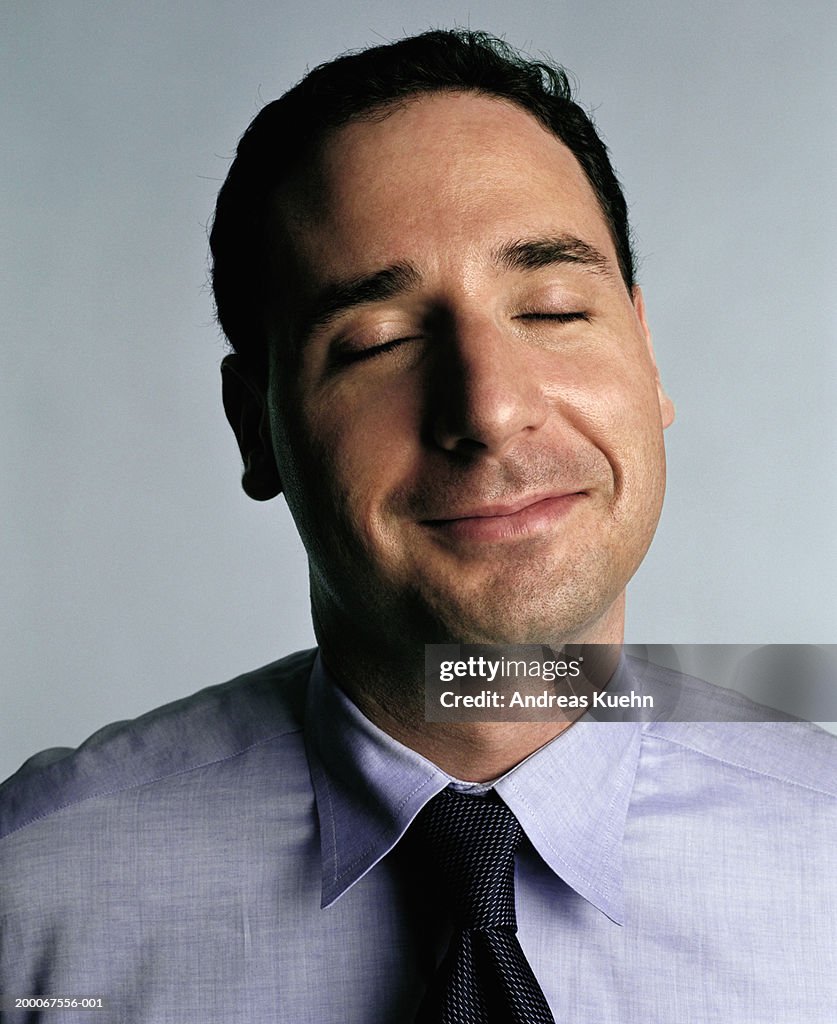 Businessman with eyes closed, smiling, close up
