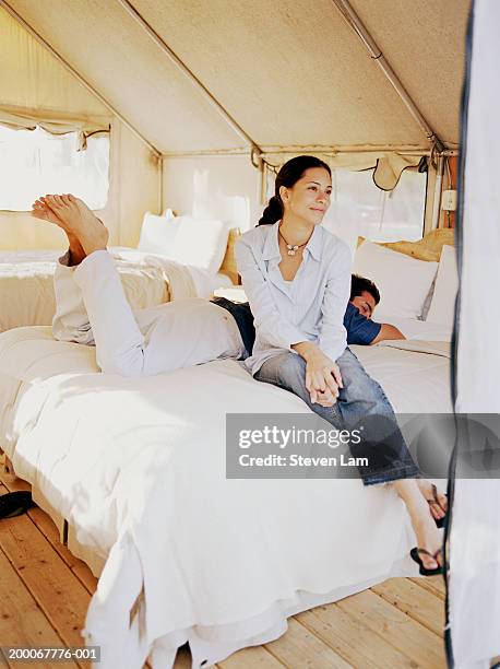 young couple in tent, man lying on bed - luxury tent stock pictures, royalty-free photos & images