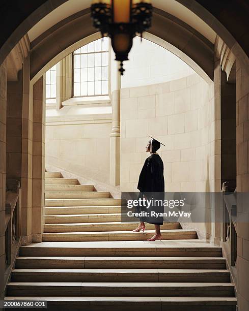 women wearing graduation cap and gown, ascending staircase, rear view - toga fotografías e imágenes de stock