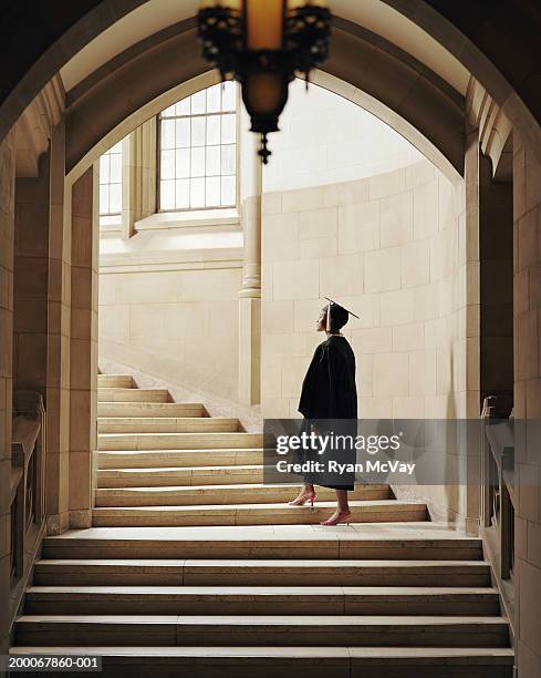 women wearing graduation cap and gown, ascending staircase, rear view - black woman graduation stock pictures, royalty-free photos & images