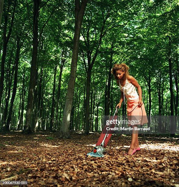 young woman vacuuming fallen leaves on forest floor - out of context foto e immagini stock