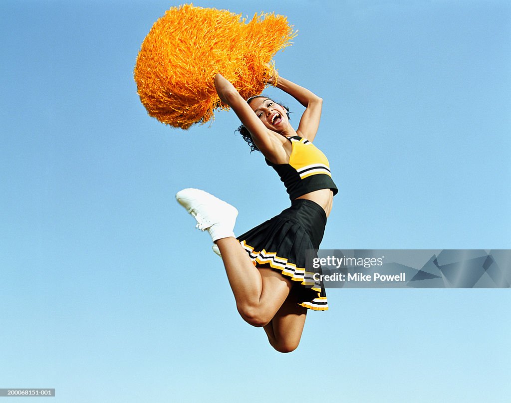 Cheerleader Jumping In Mid Air Holding Pompoms Portrait High-Res