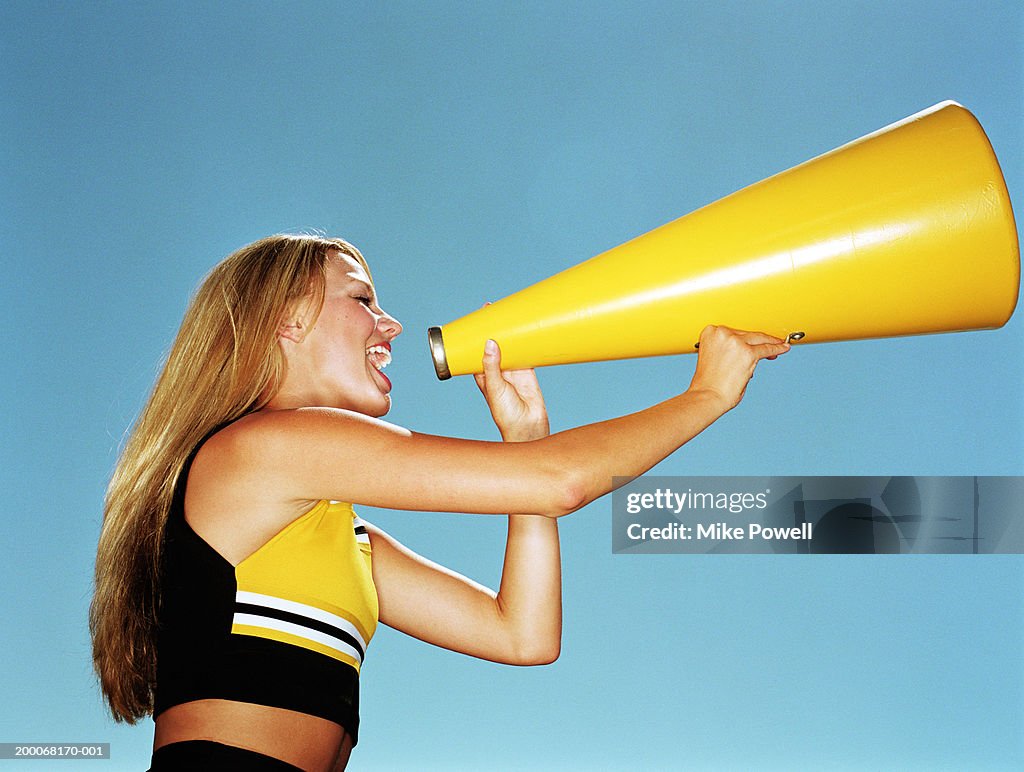 Cheerleader yelling through megaphone, low angle, side view