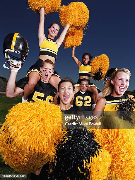 cheerleaders celebrating with football players on field, portrait - pom pom stock pictures, royalty-free photos & images
