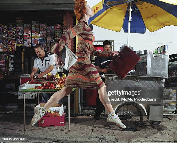 businesswoman with newspaper and briefcase leaping across sidewalk - people stand stock-fotos und bilder