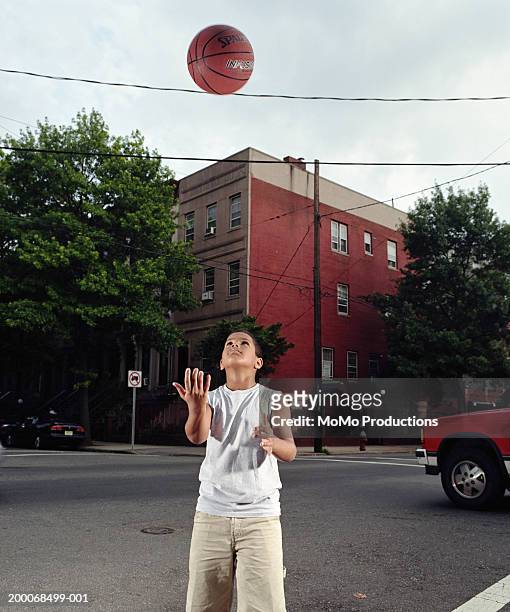 boy (8-10) throwing basketball in air - wire balls stockfoto's en -beelden