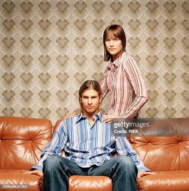young couple on sofa, woman sitting on back of sofa, portrait - simulates stock pictures, royalty-free photos & images