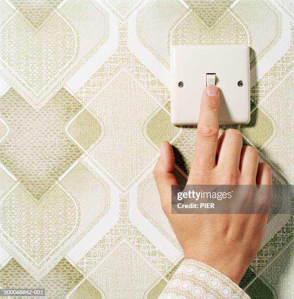 man pressing light switch on patterned wall, close-up - switching stock pictures, royalty-free photos & images