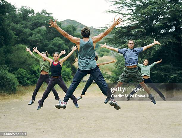 man leading group of people in boot camp exercises, rear view - jumping jack stock pictures, royalty-free photos & images