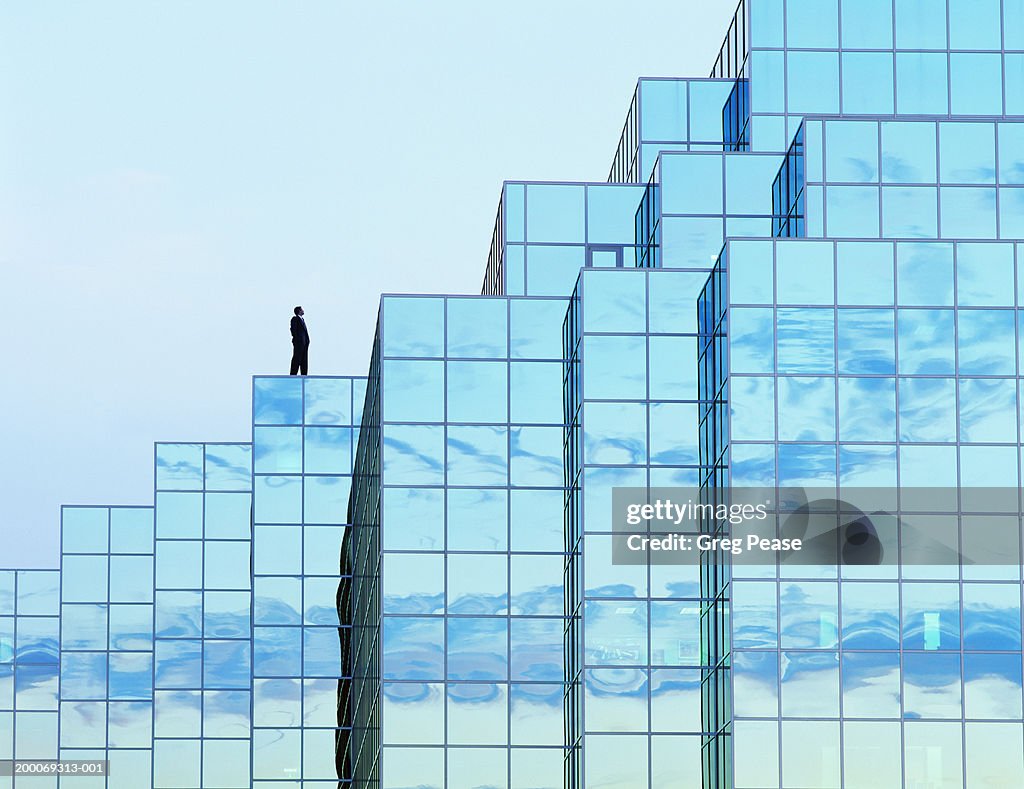 Man standing on office building roof (digital composite)
