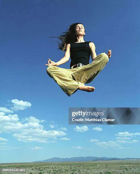 woman in yoga position in mid air - schneidersitz stock-fotos und bilder