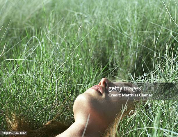woman with eyes closed lying in grass, close up - a woman lying in the grass sleeping close up stockfoto's en -beelden