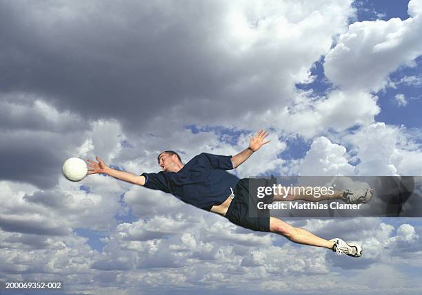 man catching soccer ball in mid air - sich zu boden werfen stock-fotos und bilder