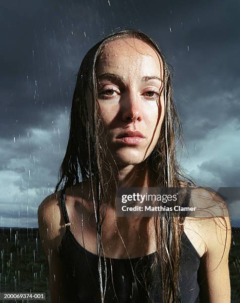 young woman standing in rain, portrait - empapado fotografías e imágenes de stock