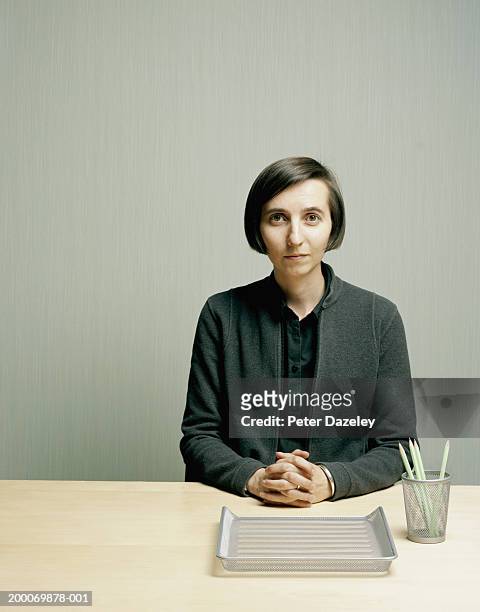 woman at desk, hands clasped, portrait - nerd woman stock-fotos und bilder