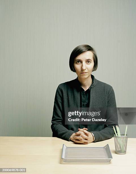 woman at desk, hands clasped, portrait - boring portrait imagens e fotografias de stock