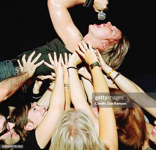 male singer with microphone, crowd surfing - crowd surfing stock pictures, royalty-free photos & images