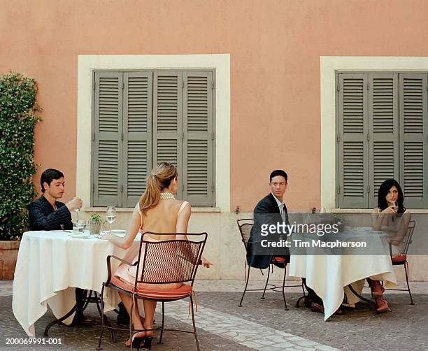 two couples at cafe tables, woman looking at man at opposite table - amore a prima vista foto e immagini stock
