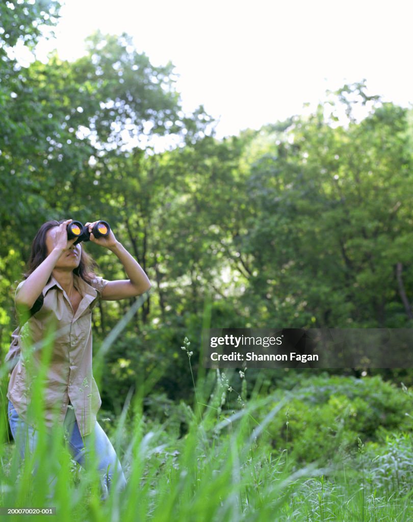 Woman in field looking through binoculars