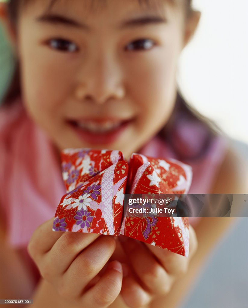 Girl (8-10) holding folded  origami paper  fortune toy, portrait