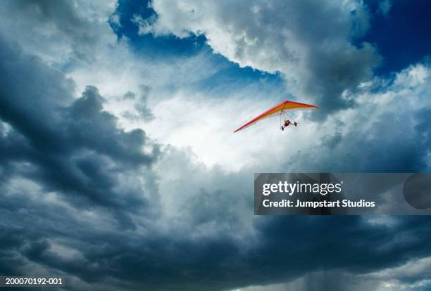 man hanggliding through clouds in sky, low angle view - hängegleiter stock-fotos und bilder
