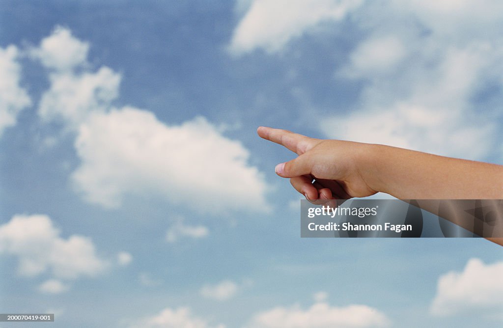 Girl (8-10) pointing at clouds, close up