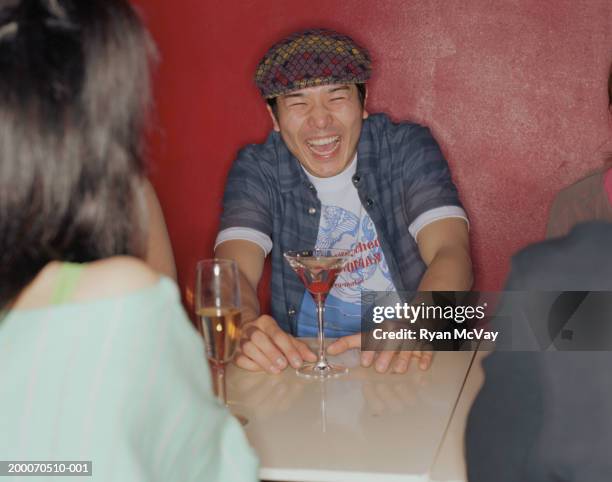 young man sitting at table with friends in nightclub, laughing - drunk stockfoto's en -beelden