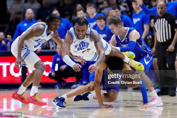 Dayvion McKnight of the Xavier Musketeers and Trey Alexander of the Creighton Blue Jays dive for a loose ball in the second half at the Cintas Center...