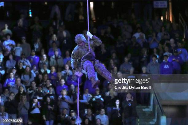Member of the Xavier University R.O.T.C. Rappels from the ceiling to deliver the game ball before the game between the Creighton Blue Jays and the...