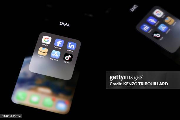 This photo taken on February 12, 2023 in Brussels shows reflexions on a smartphone screen of logos of online platforms google, facebook, linkedin,...